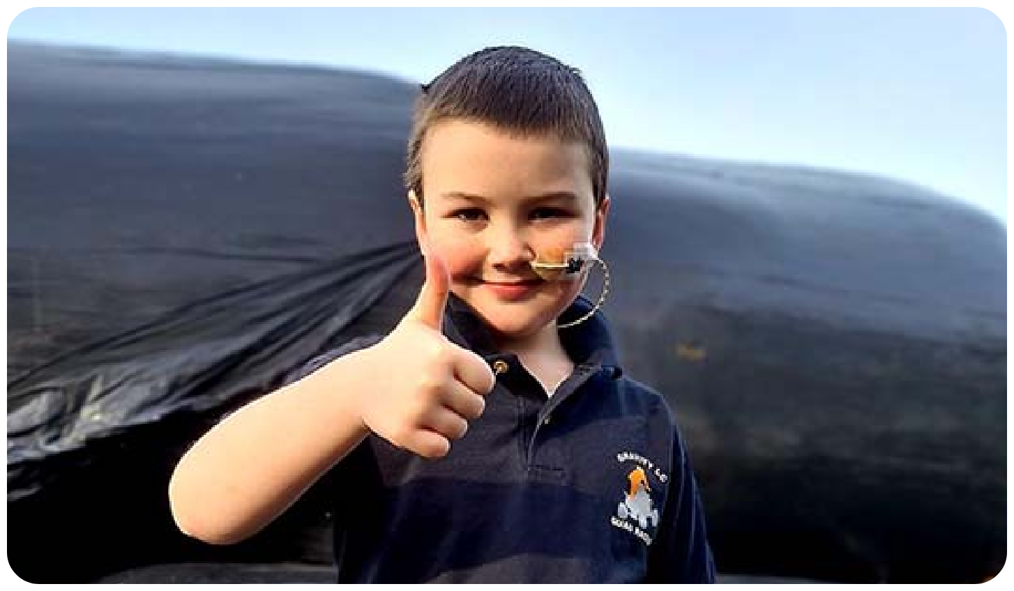 young boy with thumbs up to camera